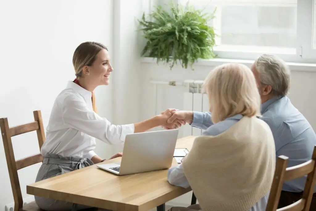 A woman shaking hands with another person at a table.